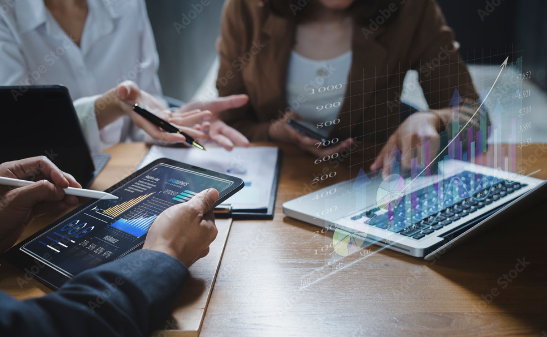 Three people in a meeting with a tablet and laptop